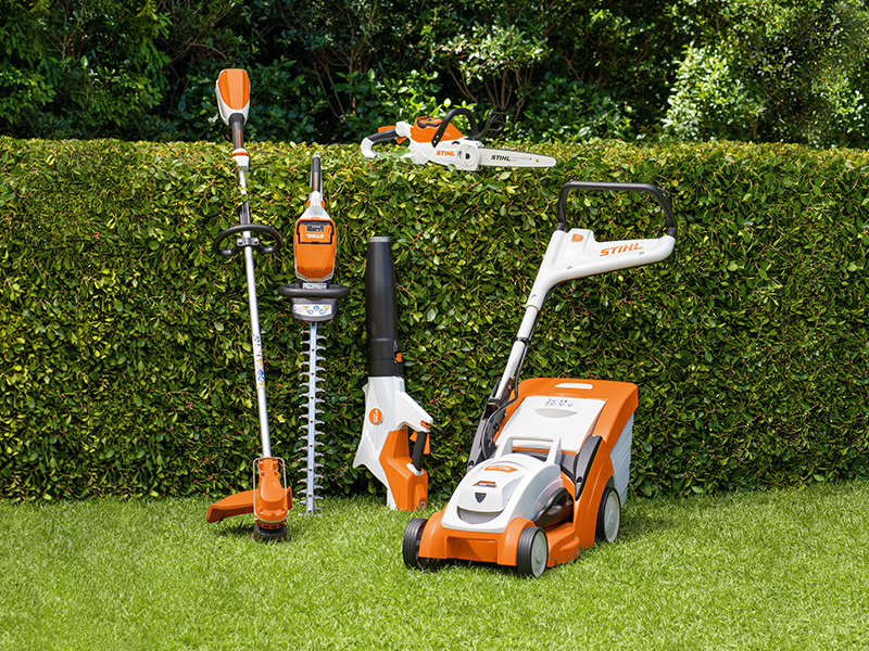 STIHL AK -sarja pensasaidan edessä, mukaan lukien FSA 60 R, HSA 60, BGA 60, MSA 70, RMA 339 C