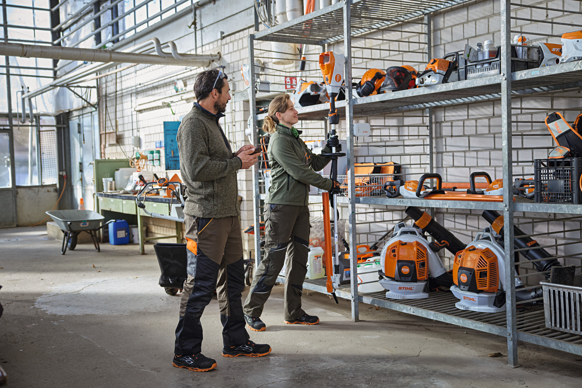 Maisemointialan ammattilaiset varastossa tarkistamassa laitteen tilaa STIHL connected -sovelluksella