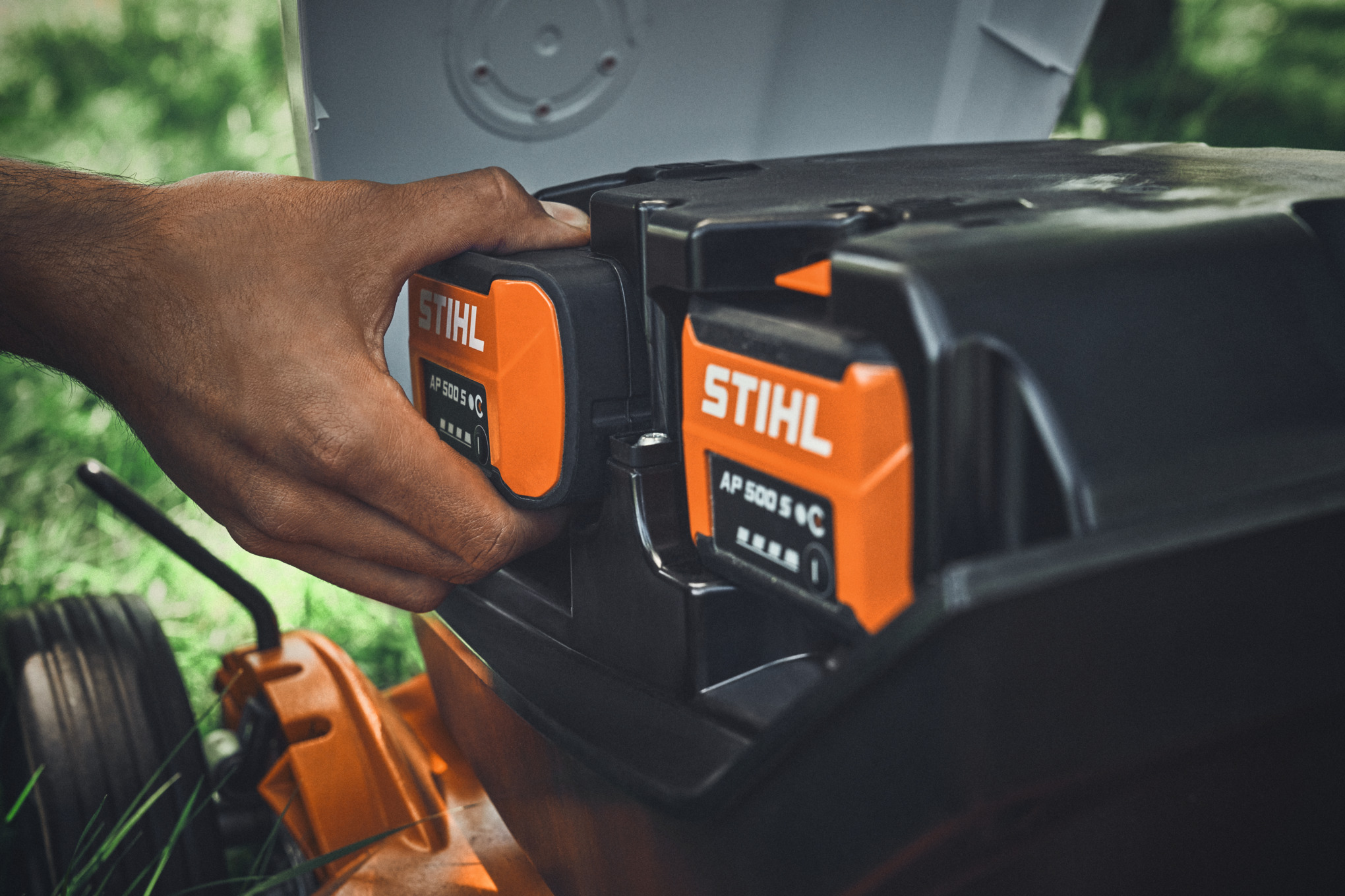 Henkilö asettaa STIHL AP 500 S -akun STIHLin akkukäyttöiseen ruohonleikkuriin.