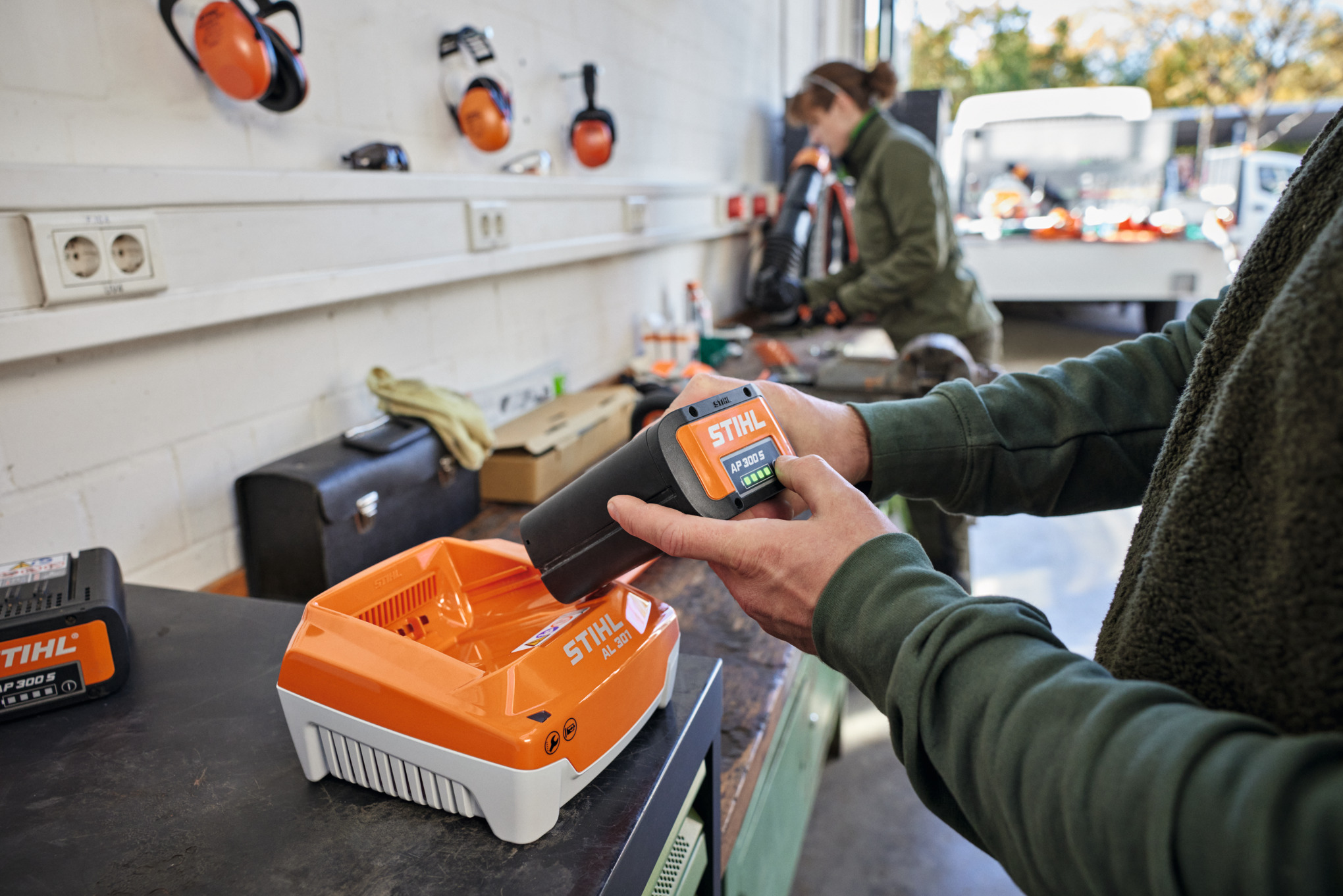 Yksi henkilö asettaa STIHL AP 300 S -akun STIHL AL 301 -pikalaturiin