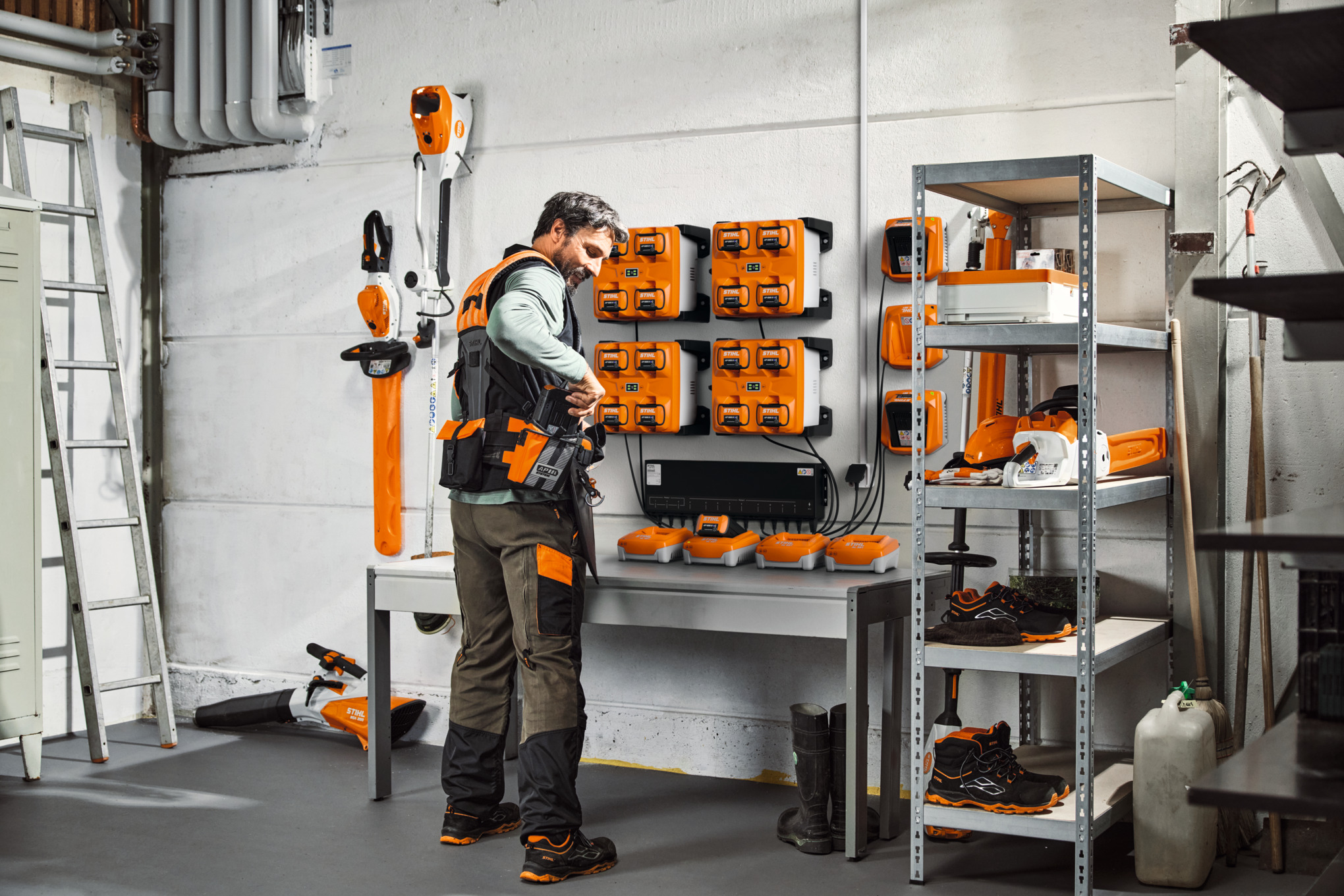 STIHL-työkalujen ja akkujen varastohuoneessa oleva mies käyttää modulaarista STIHL ADVANCE X-Flex -valjasjärjestelmää.