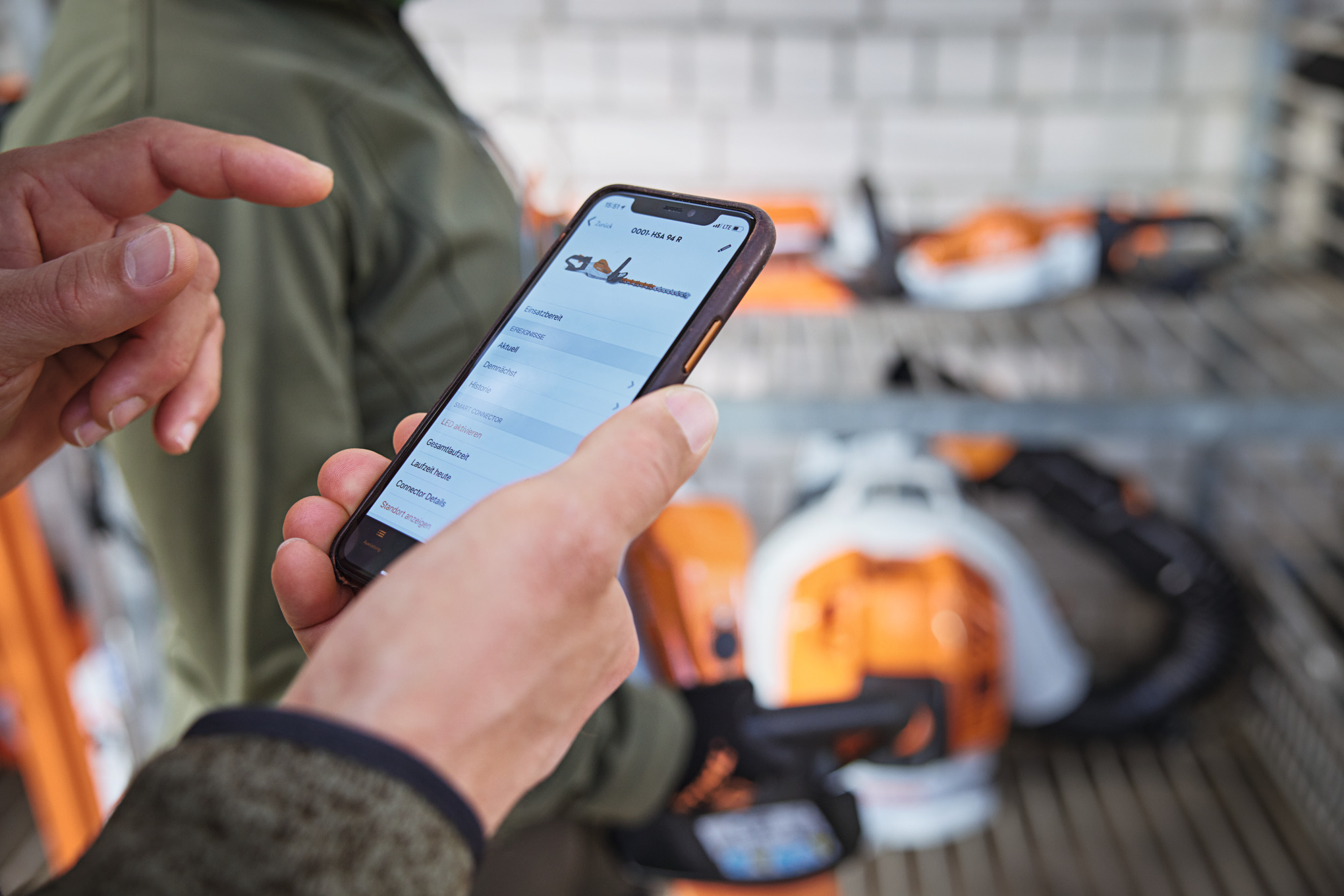 Älupuhelinta käyttävä henkilö, joka katsoo moottorisahaa STIHL connected -sovelluksessa