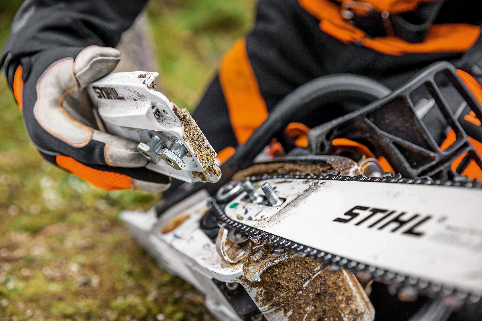 Lähikuva ketjupyörän suojuksen irrottamisesta bensiinikäyttöisestä STIHL MS 261 C-M -moottorisahasta 