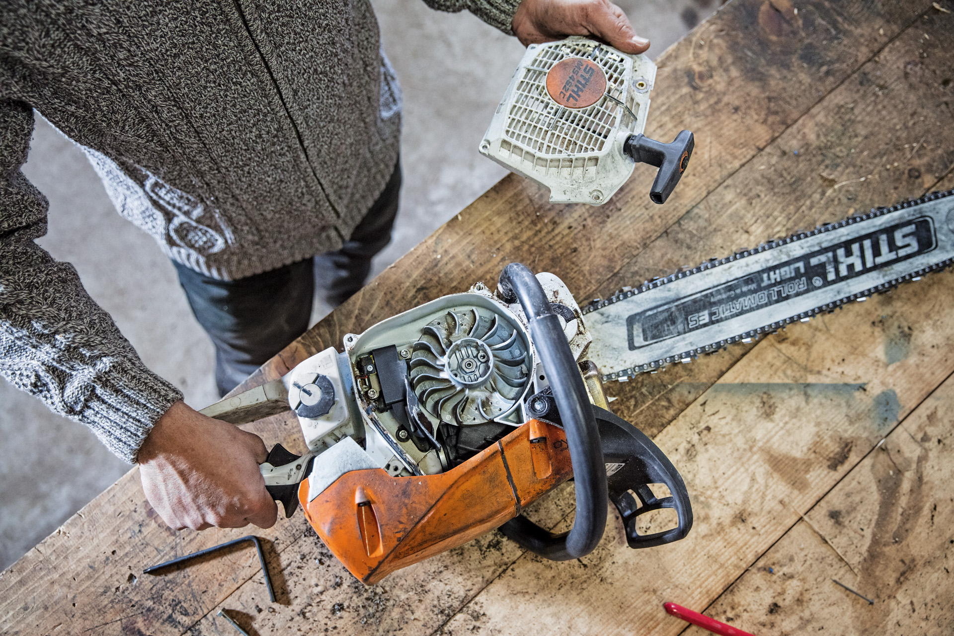 Henkilö huoltaa STIHL MS 462 C-M -bensiinikäyttöistä moottorisahaa työpöydällä.