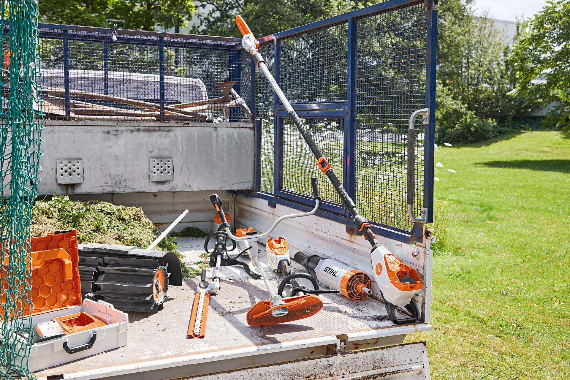 Ajoneuvo, jossa on STIHL HTA 135 -oksasaha, HLA 135 -pensasleikkuri, FSA 135 -moottorileikkuri ja KMA 135 lastausalueella