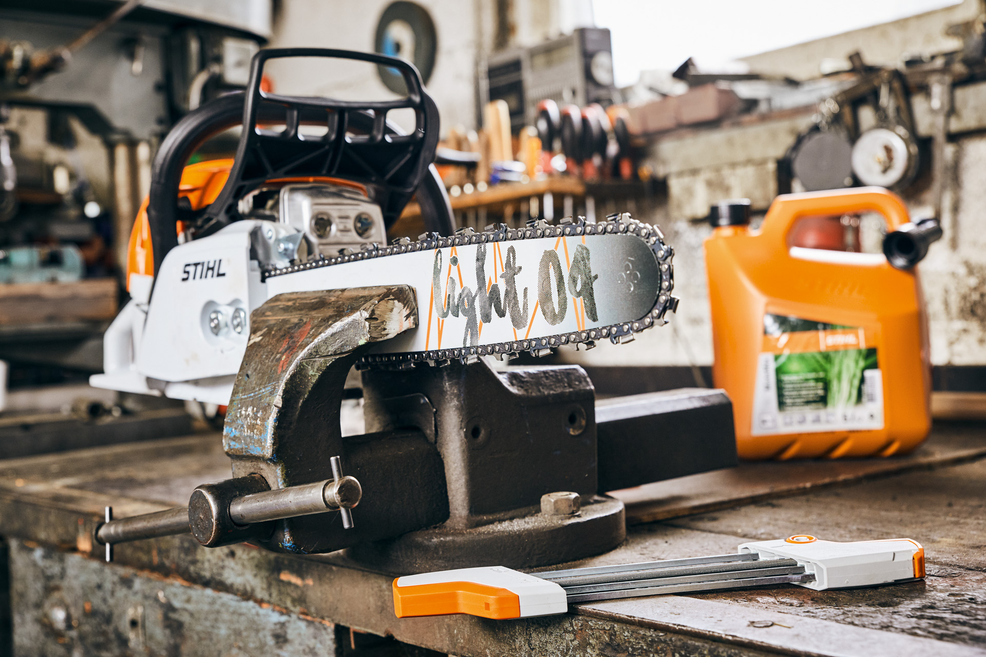 Bensiinikäyttöinen moottorisaha STIHL MS 261 C-M, jossa Light 04 -terälaippa STIHL MotoMix -polttoaineseoksen vieressä ennen teroitusta