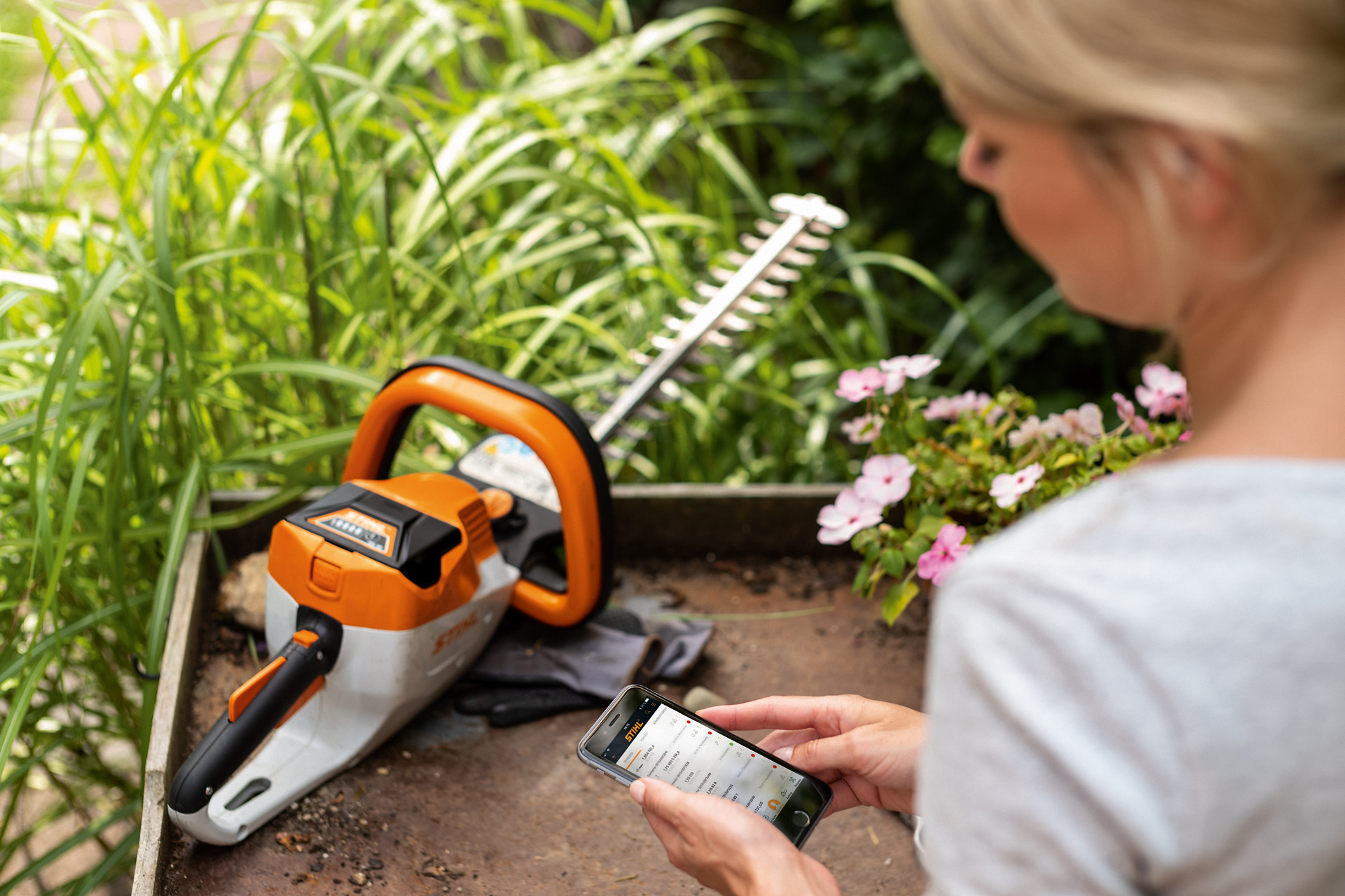 Nainen rekisteröimässä STIHL-pensasleikkuria älypuhelimen STIHL-sovelluksella
