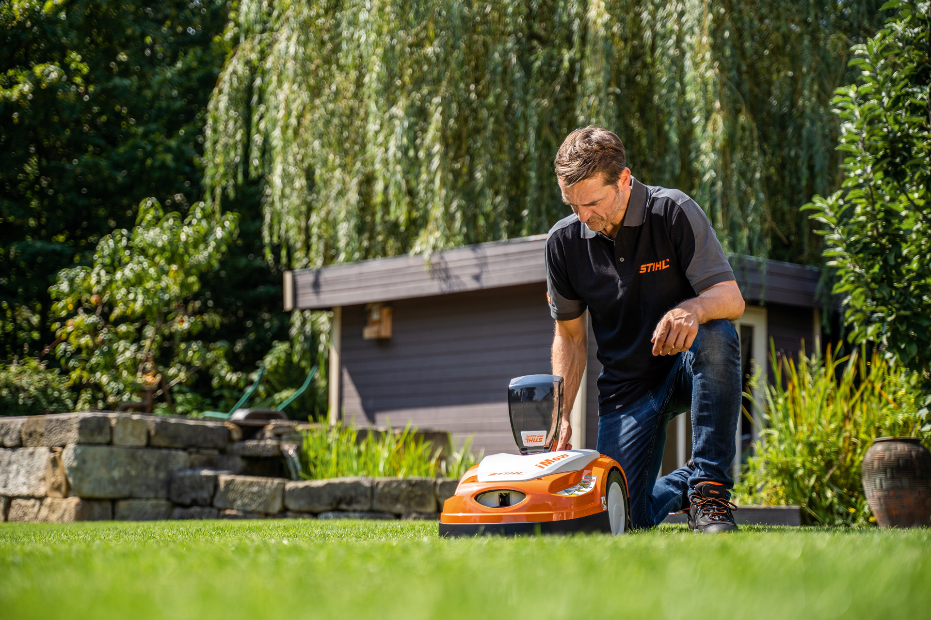STIHL-jälleenmyyjä ohjelmoimassa STIHL iMOW -robottiruohonleikkurin leikkuusuunnitelmaa puutarhassa
