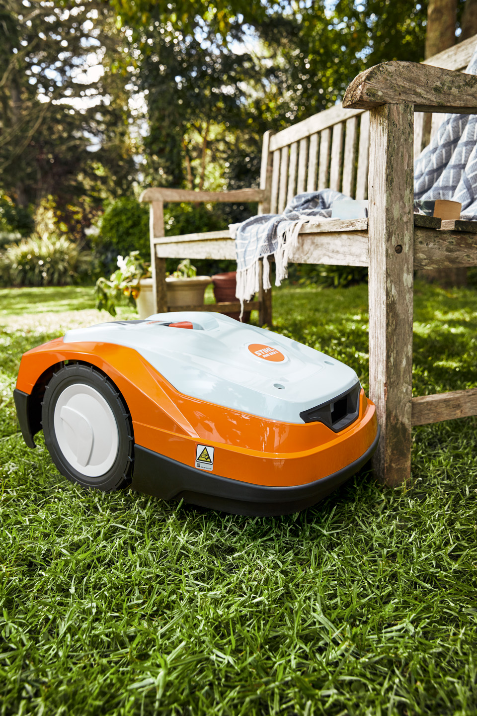 STIHL iMOW® RM 522 -robottiruohonleikkuri vihreällä nurmikolla penkin vieressä