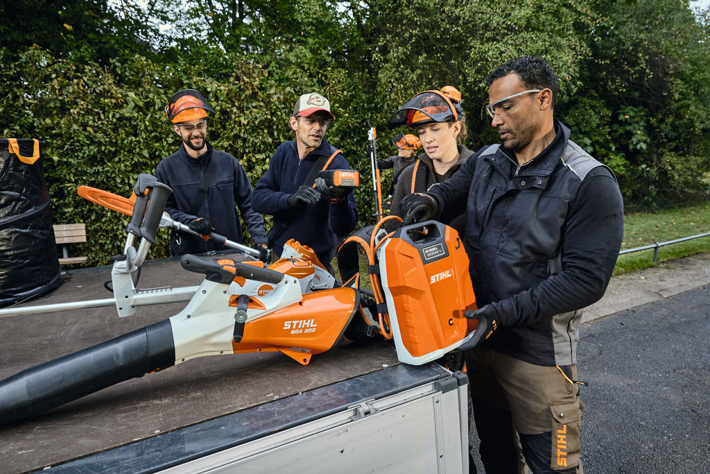 Maisemointialan ammattilaisten tiimi purkaa STIHL-akkukäyttöiset ammattilaislaitteensa ajoneuvon lastausalueelta.